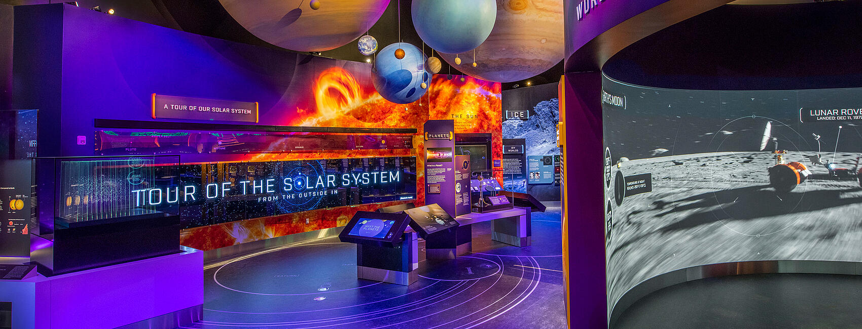 A photo of of exploring the planets gallery. A large sign reads Tour the Solar System and planets hang from above.